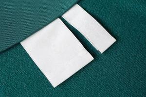 étiquette de vêtements de soin de lessive blanche vierge sur fond de texture de tissu vert photo