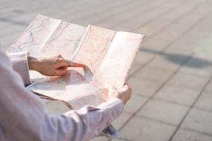 point de main de femme asiatique sur la carte lors d'un voyage en plein air le jour. photo