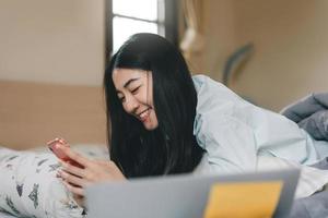 heureuse jeune adulte seule femme célibataire utilisant un smartphone le matin pour l'application de message social discuter avec un ami pour la santé mentale. photo