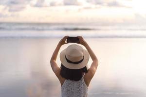 vue arrière d'une jeune femme asiatique adulte se détendre dans la nature sur le sable de la plage photo