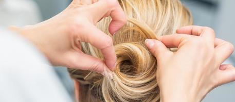 coiffeur faisant la coiffure de mariage de la mariée photo