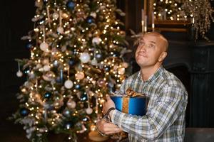 un homme avec un cadeau près du sapin de noël photo