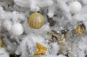 décoration de sapin de noël en gros plan. ampoule de décoration, sapin blanc, jouets et lumières de Noël dorés. utiliser pour le fond de célébration de noël et du nouvel an photo