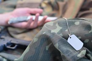 le jeton vide de l'armée du soldat militaire mort repose sur des vêtements de camouflage. suicide pendant le service militaire dans l'armée russe photo