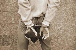 trafiquant de drogue arrêté dans les menottes de la police avec un gros paquet de drogue d'héroïne sur fond de mur sombre photo
