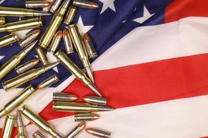 de nombreuses balles et cartouches jaunes de 9 mm et 5,56 mm sur le drapeau des États-Unis. concept de trafic d'armes à feu sur le territoire américain ou opérations spéciales photo