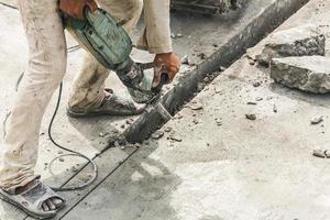 travailleur de la construction à l'aide d'un marteau-piqueur forant une surface en béton photo