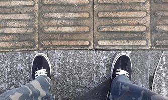 une paire de chaussures noires avec un pantalon militaire sur le bord de la route photo