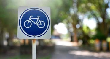 panneau de signalisation de piste cyclable sur poteau métallique, mise au point douce et sélective, arrière-plan flou de la route principale. photo