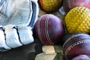 entraînement des équipements de sport de cricket au sol, ballon en cuir, gants et batte, mise au point douce et sélective sur le ballon. photo