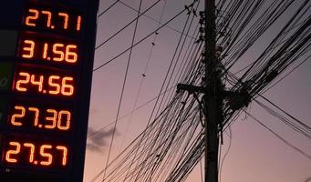 panneau numérique de prix de l'essence près du poteau électrique qui a des lignes téléphoniques de cordage et de câblage dans les zones urbaines de thaïlande. photo
