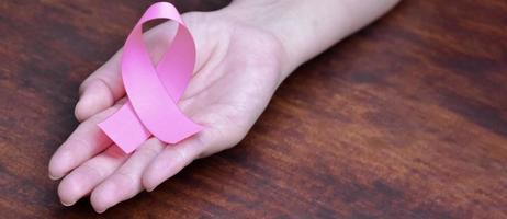 ruban rose sur la paume de la femme, concept pour soutenir et encourager les femmes atteintes d'un cancer du sein dans le monde entier. photo
