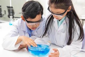 jeune étudiant asiatique garçon et fille portant un google protecteur pendant qu'il étudie et fait des expériences scientifiques en classe avec l'enseignant. moment d'apprentissage et de plaisir. concept de classe de chimiste ou de biologie. photo