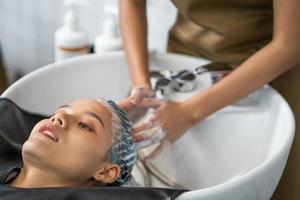 les belles femmes caucasiennes se sentent détendues et à l'aise tout en se lavant les cheveux avec du shampoing et des massages. studio de salon de coiffure avec concept de cheveux élégant, beauté et mode. photo