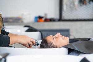 les belles femmes caucasiennes se sentent détendues et à l'aise tout en se lavant les cheveux avec du shampoing et des massages. studio de salon de coiffure avec concept de cheveux élégant, beauté et mode. photo