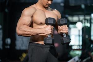 beaux hommes caucasiens adultes transpirant tout en soulevant l'entraînement d'haltères pour la partie musculaire du biceps du bras à l'intérieur de la salle de fitness. entraînement sportif d'athlète de musculation pour la force corporelle et une bonne santé. photo