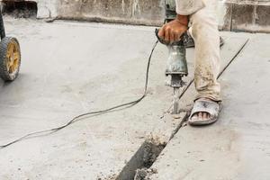 travailleur de la construction à l'aide d'un marteau-piqueur forant une surface en béton photo