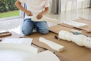 homme assemblant des meubles de table blancs à la maison photo