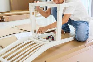 homme assemblant des meubles de chaise blanche à la maison photo