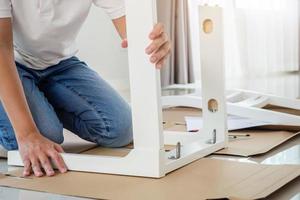 homme assemblant des meubles de chaise blanche à la maison photo