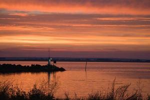 coucher de soleil en suède au port du lac vaettern. phare en arrière-plan photo