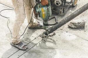 travailleur de la construction à l'aide d'un marteau-piqueur forant une surface en béton photo