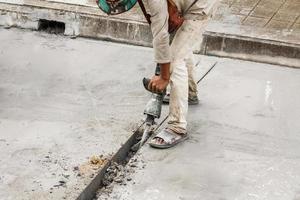 travailleur de la construction à l'aide d'un marteau-piqueur forant une surface en béton photo