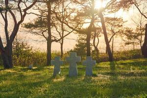 croix de pierre au coucher du soleil dans le cimetière militaire allemand, europe photo