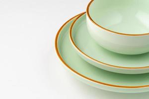 un ensemble de vaisselle en céramique vert pastel aux contours orange. fermer