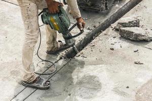 travailleur de la construction à l'aide d'un marteau-piqueur forant une surface en béton photo