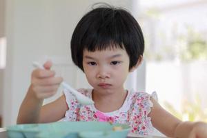 petite fille asiatique prenant son petit déjeuner photo