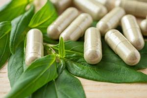 capsules de phytothérapie avec feuille d'andrographis paniculata sur table en bois photo