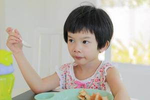 petite fille asiatique prenant son petit déjeuner photo