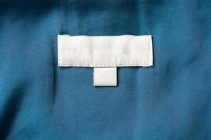 étiquette blanche de vêtements de soin de blanchisserie vierge sur fond de tissu photo