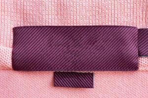 étiquette de vêtements de soin de blanchisserie rouge vierge sur fond de texture de tissu rose photo
