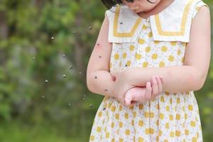 une petite fille a une allergie cutanée qui démange et se gratte le bras avec une piqûre de moustique photo