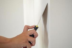 homme réparant un mur blanc fissuré avec une spatule photo