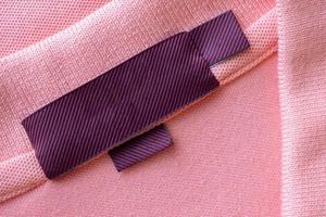 étiquette de vêtements de soin de blanchisserie rouge vierge sur fond de texture de tissu rose photo