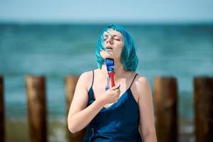 Artiste de performance artistique femme aux cheveux bleus en robe enduite de peintures à la gouache bleue sur son corps photo