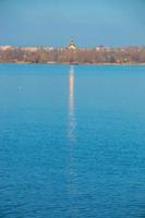 la coupole dorée de l'église orthodoxe, dressée sur les rives du fleuve, se reflète à la surface de l'eau. passerelle dorée du dôme de l'église à la surface de la rivière. photo