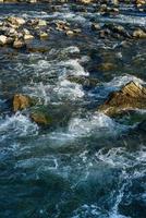 couler, pour une rivière orageuse parmi les rochers dans le parc d'automne par une chaude journée photo