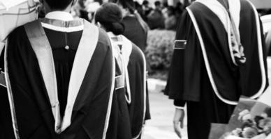 noir et blanc un groupe de diplômés masculins et féminins portant des robes noires à l'extérieur un jour de pluie dans le concept universitaire obtenant un diplôme. photo