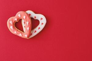 deux décorés de glaçage et de biscuits en forme de coeur glacés sur fond rouge avec espace de copie. concept de nourriture saint valentin photo