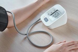 femme mesurant la pression artérielle avec un moniteur de pression numérique sur fond bleu. soins de santé et concept médical photo