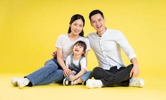 image d'une famille asiatique assise ensemble heureuse et isolée sur fond jaune photo