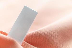 étiquette de vêtements de soin de lessive blanche vierge sur fond de texture de tissu rose photo