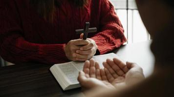 les chrétiens sont des fidèles se donnent la main pour prier et chercher les bénédictions de dieu sur la table en bois photo