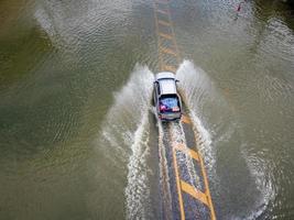 routes inondées, des gens avec des voitures qui traversent. la photographie aérienne par drone montre les rues inondées et les voitures des gens qui passent, éclaboussant l'eau. photo