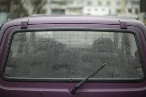 la vitre de la voiture est plus claire sous la pluie. voiture mouillée dans le parking. détails des anciens transports. photo