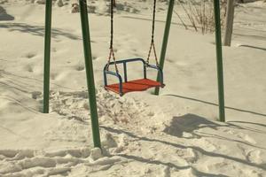 balançoire en hiver. aire de jeux pour enfants dans la neige. se balance sur des cordes. photo